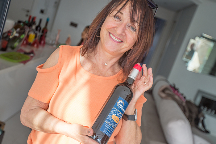 Costa Blanca Kundenvideo: Sabine hält eine Flasche Inmo Investments Wein in den Händen